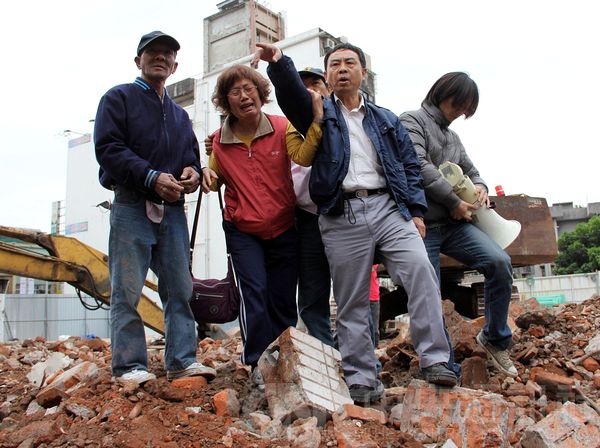 台北士林文林苑都更案，北市府針對未搬遷戶進行拆除後，王家發起回家活動，由住戶之一王廣樹（右2）進入工地，踩在已拆除的家中宣示回家。中央社記者張新偉攝 101年3月31日