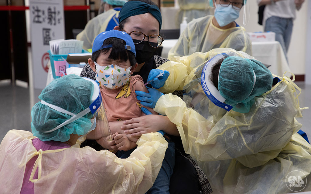 台灣4月開始進入以Omicron變異株為主的社區流行，確診個案年輕化，兒童染疫人數增加，指揮中心4月起陸續開放兒童疫苗接種。六都在端午連假設置大型疫苗接種站，提供5至11歲兒童施打輝瑞疫苗。圖為家長帶孩子到台北自由廣場，在醫護人員細心安撫下完成接種。