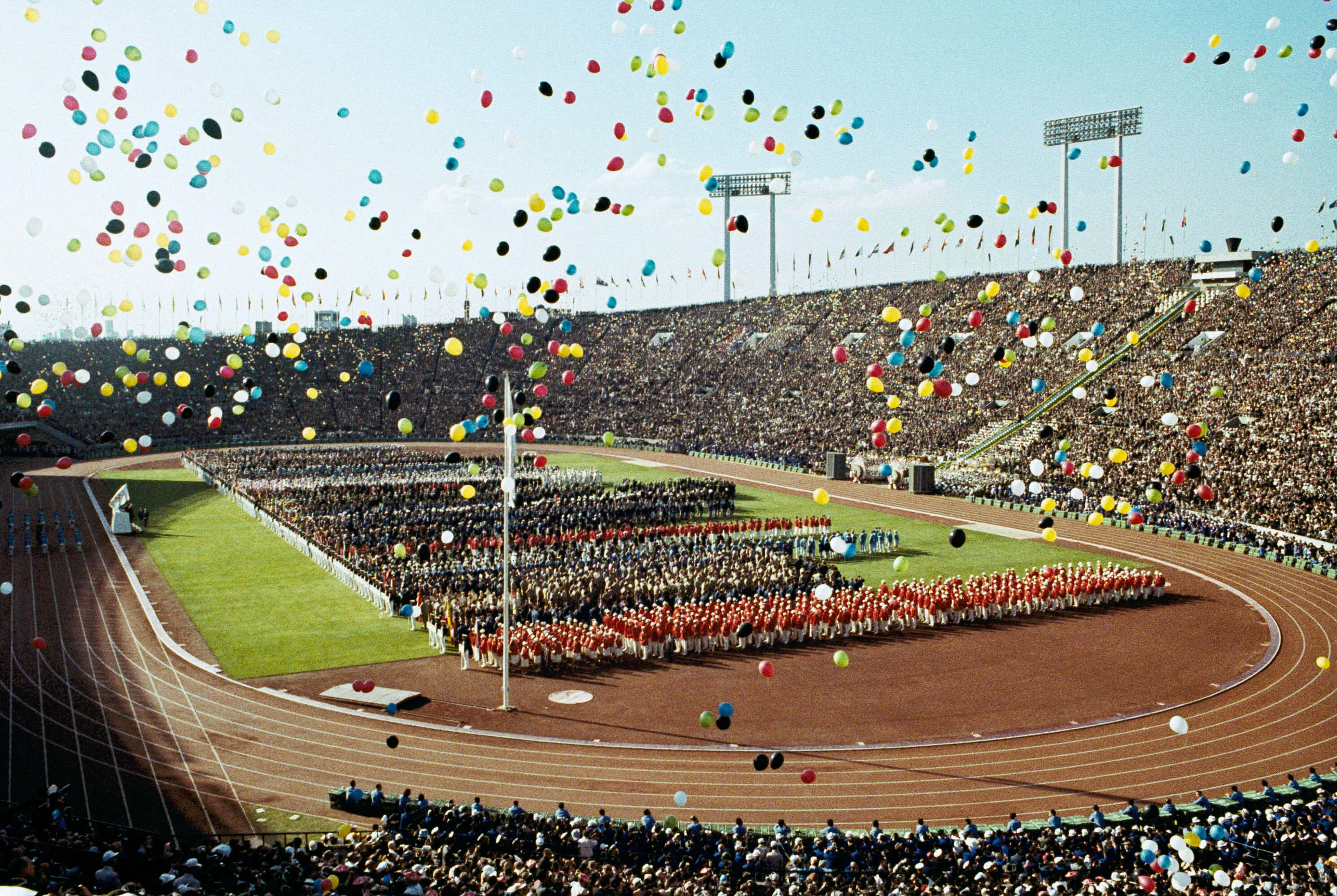 1964年夏季奧運會在東京國家體育場舉行的開幕式上，氣球飛過奧運選手和觀眾。（檔案照片／美聯社）