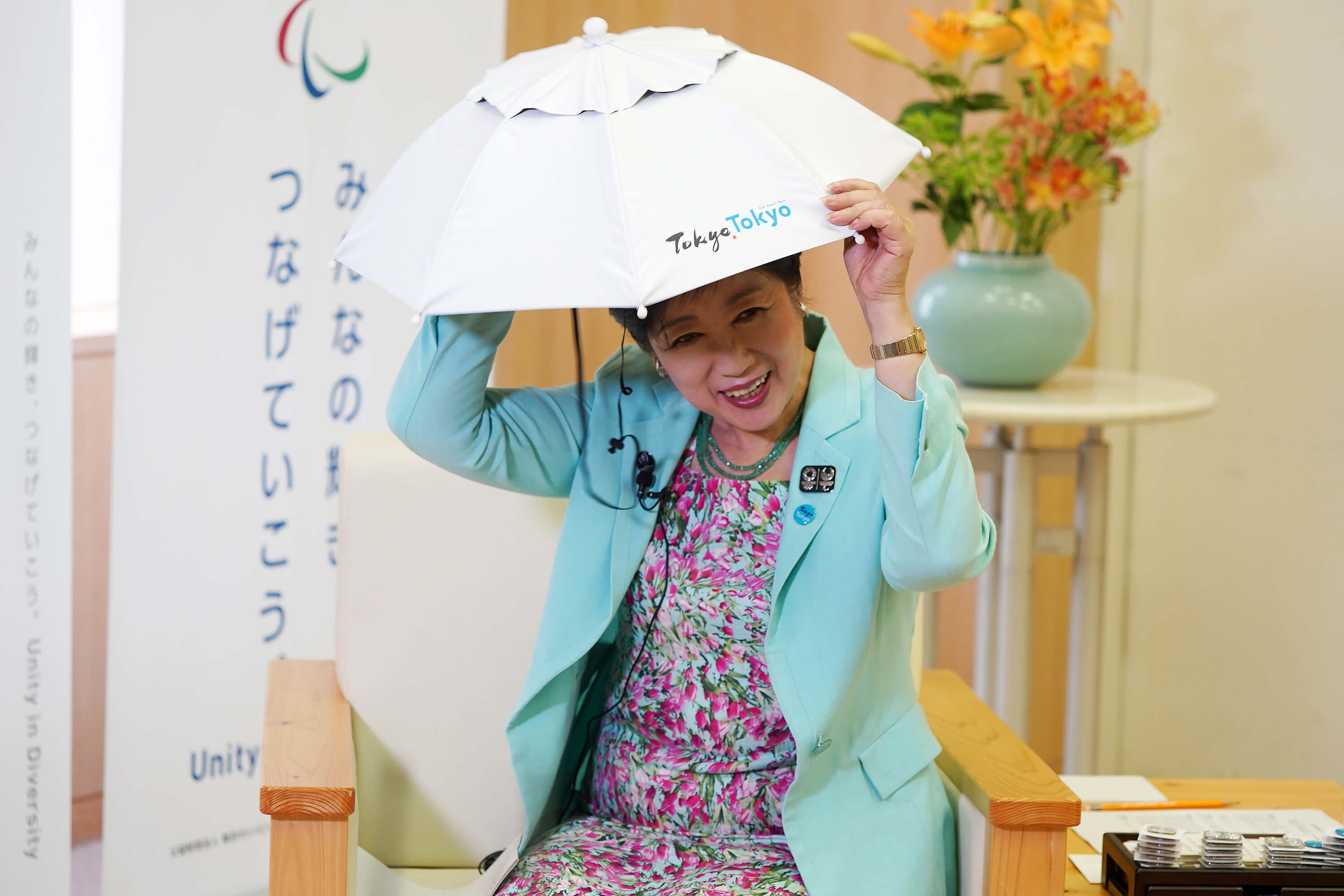 小池百合子在專訪中親自戴上抗熱傘帽，推銷東京炎夏的去暑良方。（中央社記者吳家昇攝）