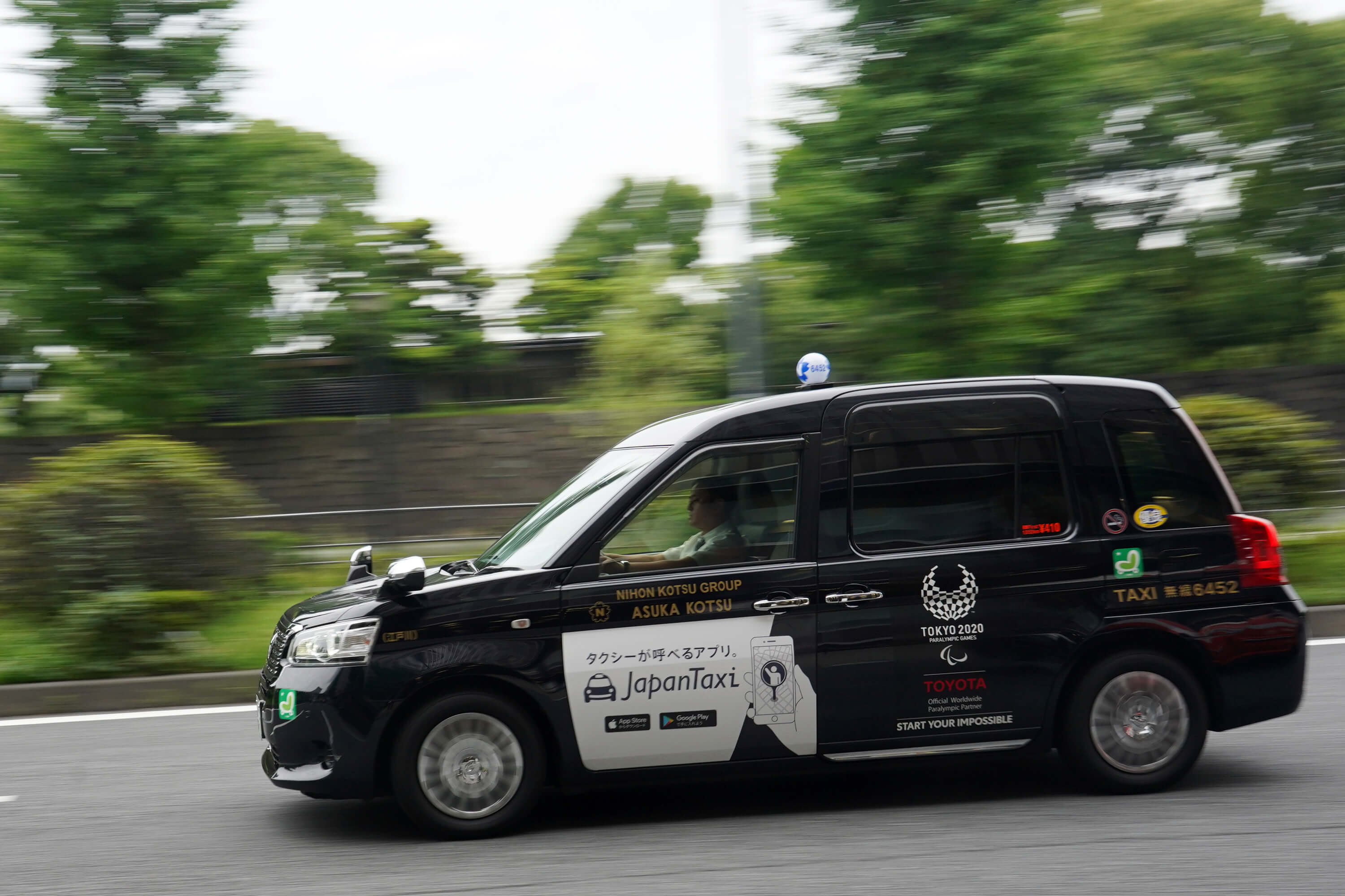 日本為奧運推出的新款計程車，車體色彩以有悠久歷史的「深藍」為底，後門貼上白色奧運徽章。（中央社記者吳家昇攝）